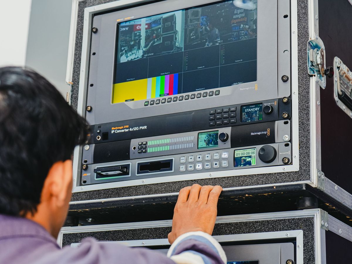 Technician operating broadcast recorders and a monitor in a flight-case rack
