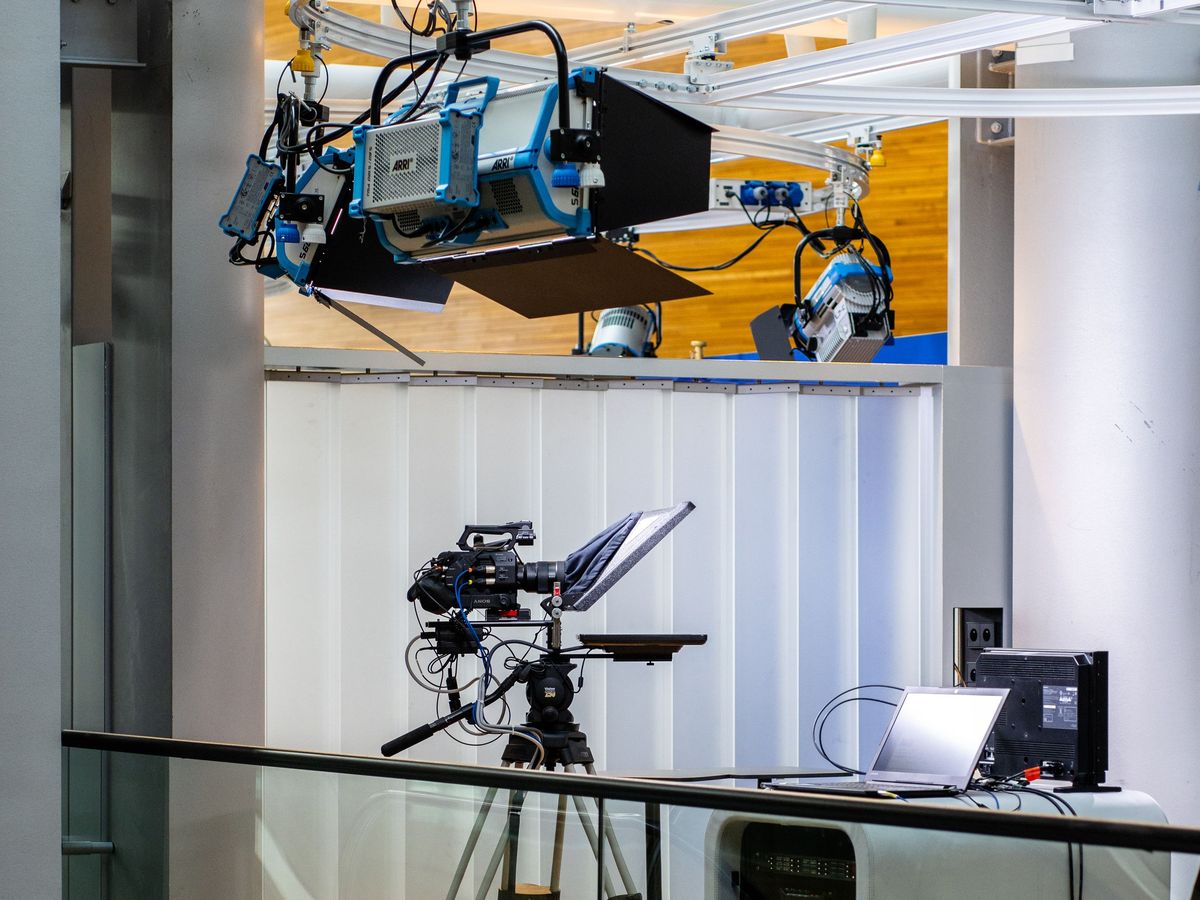 Studio camera on a pedestal with a teleprompter under ceiling-mounted studio lights